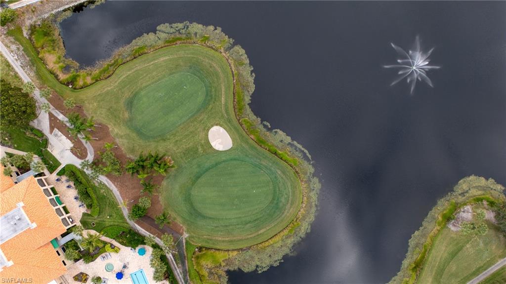 Manicured golf course greens bordering a serene water feature with a fountain