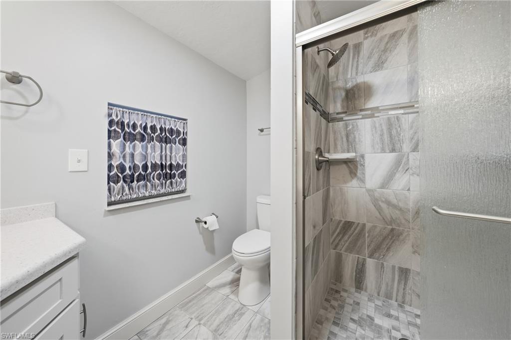 Bathroom featuring a glass-enclosed shower with tile surround, a built-in shower shelf, and a rain showerhead