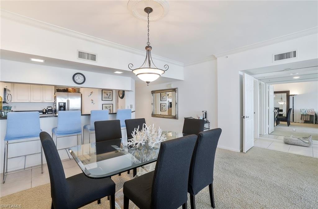 Dining space with light tile patterned floors, crown molding, light colored carpet, and recessed lighting