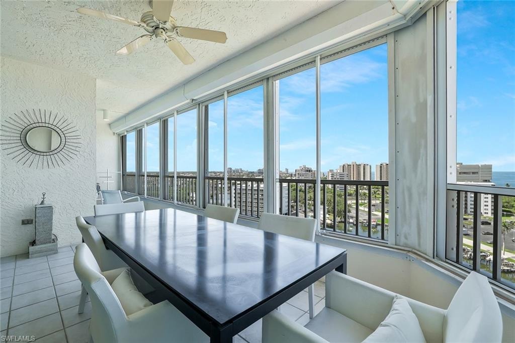 Dining area featuring a textured wall, a skyline view, ceiling fan, a textured ceiling, and tile patterned flooring