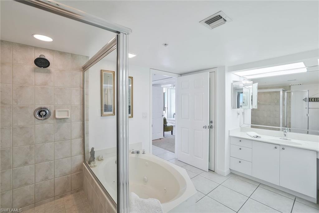 Full bathroom featuring a stall shower, a jetted tub, vanity, tile patterned floors, and recessed lighting