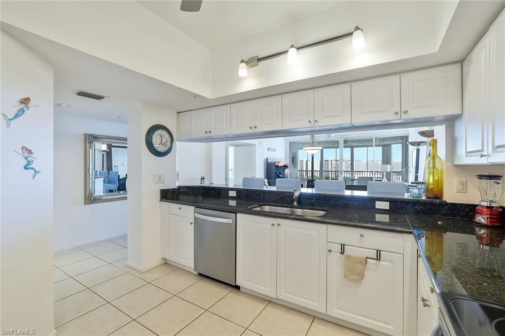 Kitchen with stainless steel dishwasher, rail lighting, white cabinetry, and light tile patterned floors