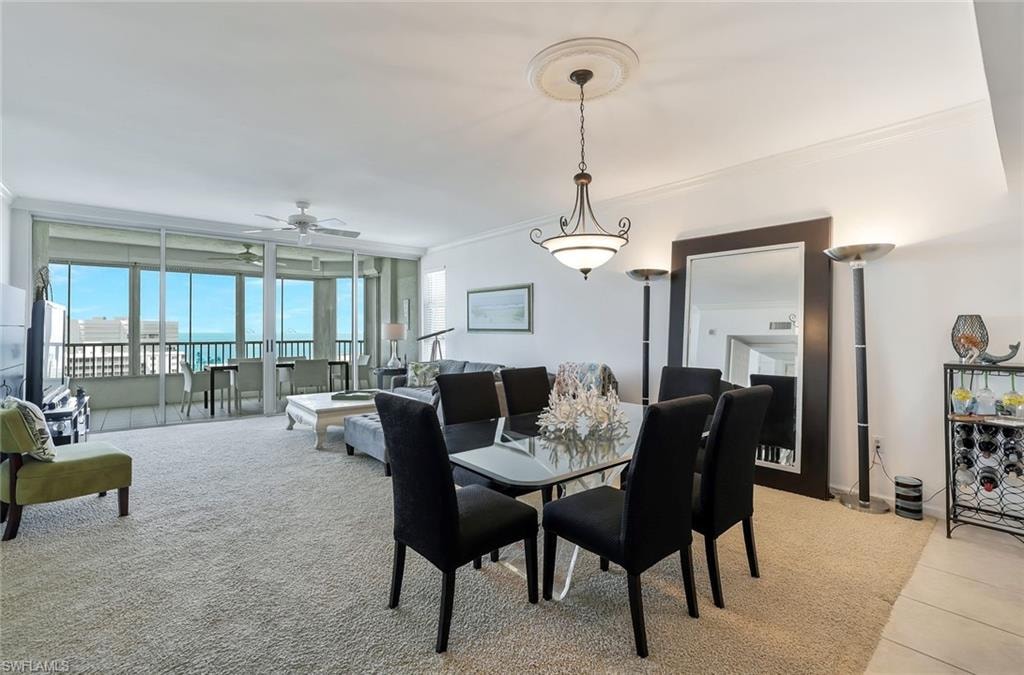 Dining space with crown molding, light colored carpet, ceiling fan, and expansive windows
