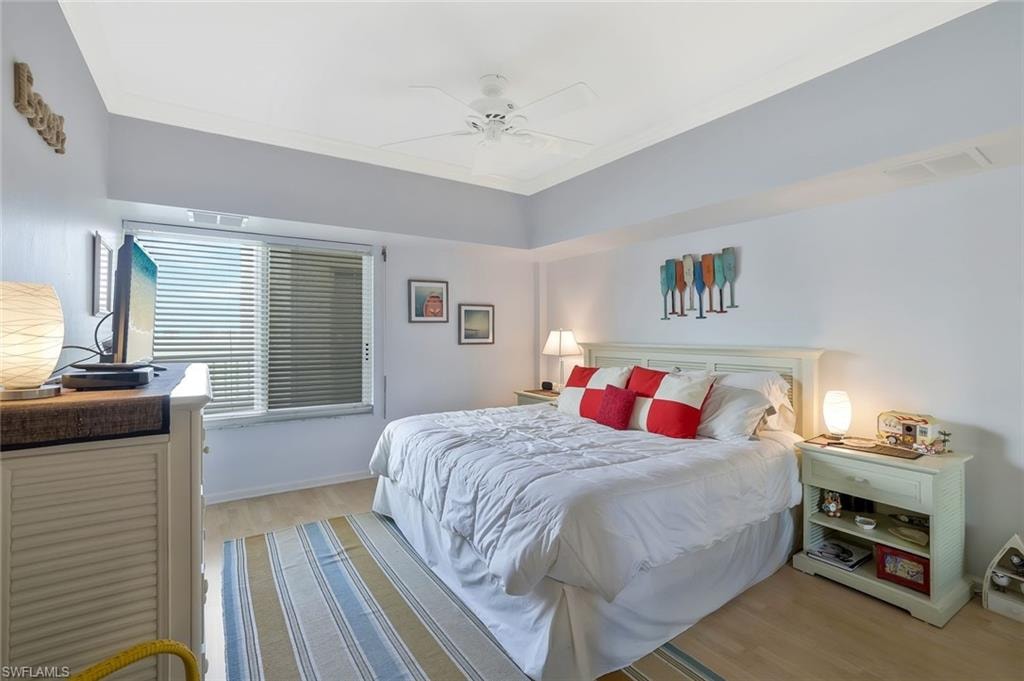 Bedroom with wood finished floors, ornamental molding, and a ceiling fan