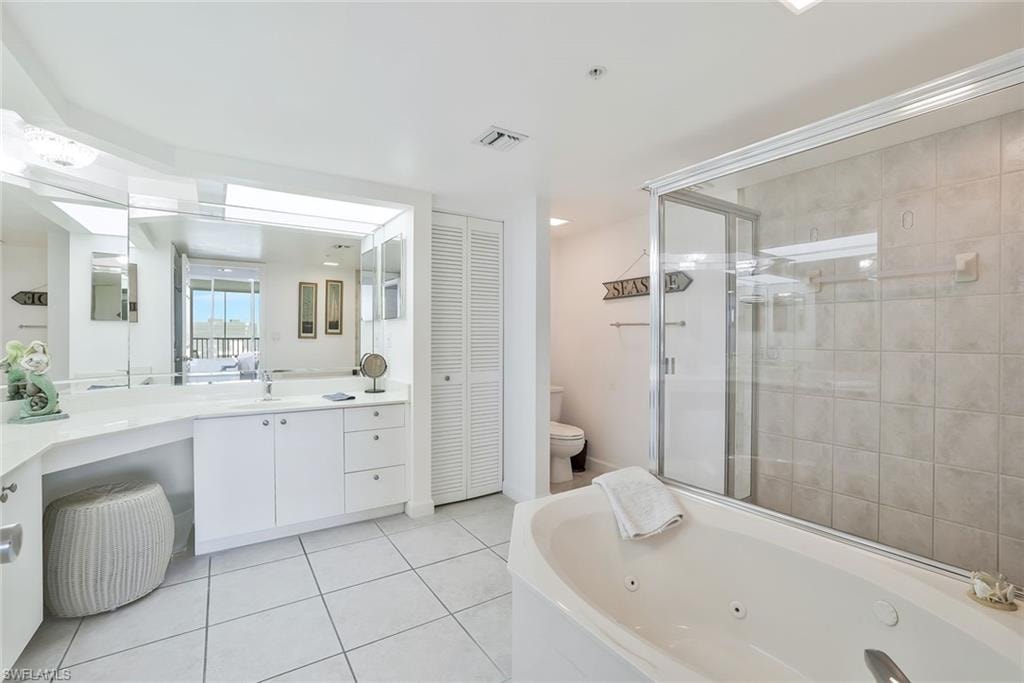 Full bathroom with a closet, a tub with jets, an enclosed shower, vanity, and tile patterned floors