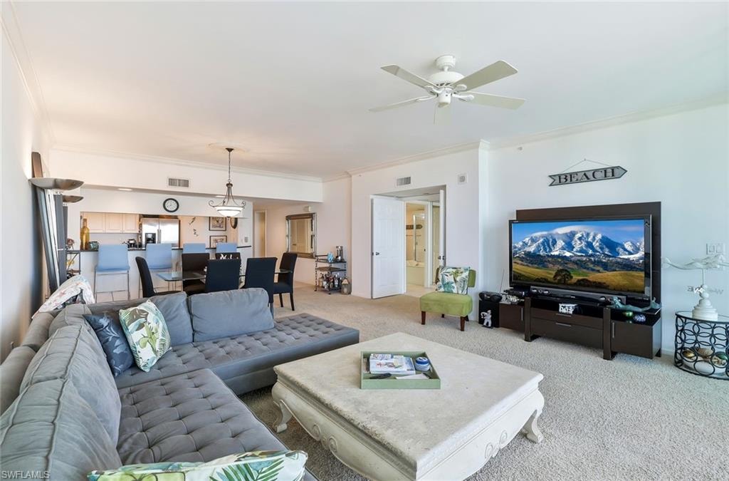 Living room featuring light carpet, ornamental molding, and ceiling fan