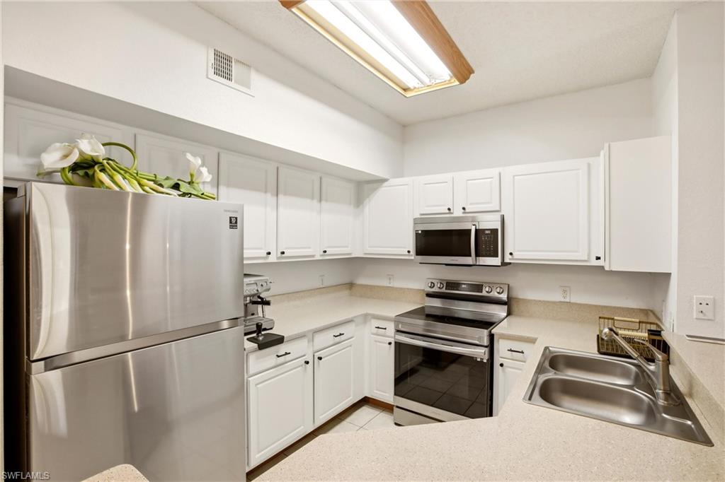 Kitchen featuring stainless steel appliances, white cabinets, light countertops, and light tile patterned floors