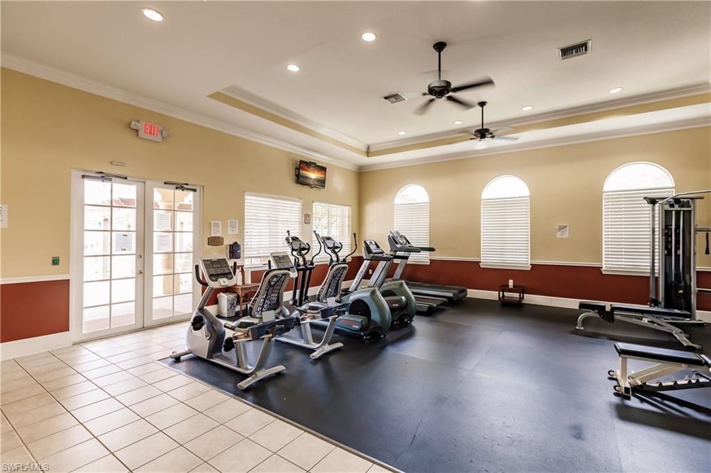 Workout area featuring ceiling fan, crown molding, a tray ceiling, and recessed lighting