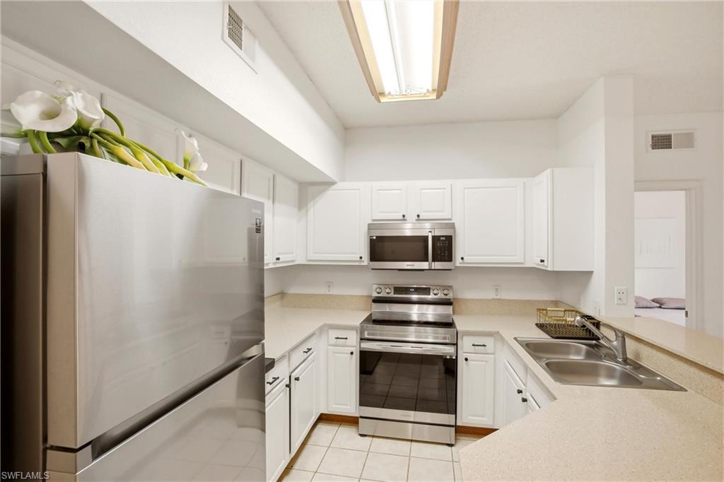 Kitchen with stainless steel appliances, light countertops, and white cabinets