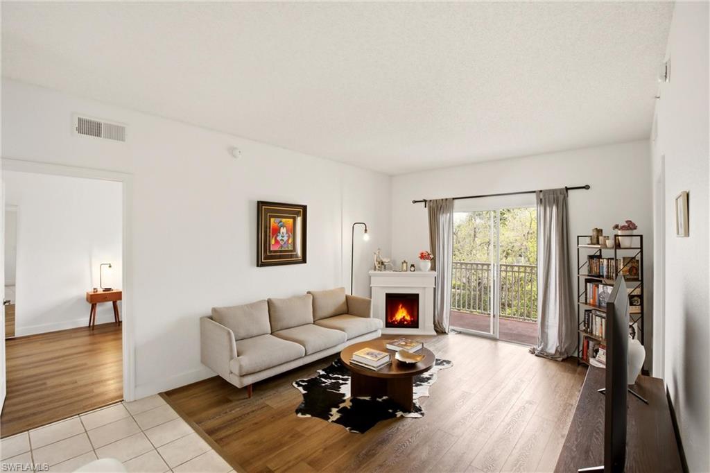 Living area with light wood-style floors and a warm lit fireplace