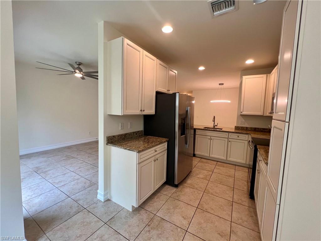 Kitchen featuring white cabinets, light tile patterned floors, sink, and ceiling fan