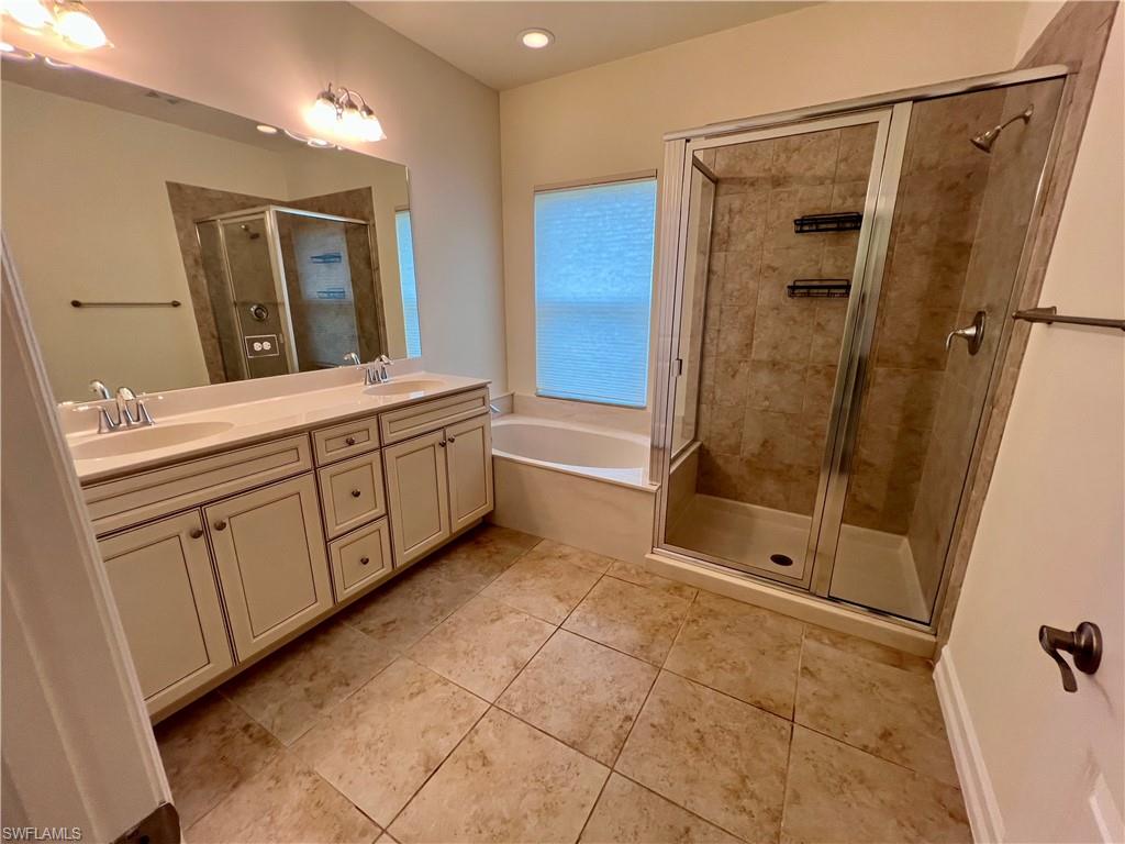 Bathroom featuring separate shower and tub, tile patterned floors, and dual bowl vanity