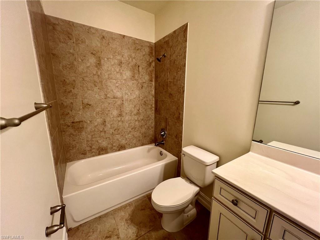 Full bathroom with vanity, toilet, tile patterned floors, and tiled shower / bath