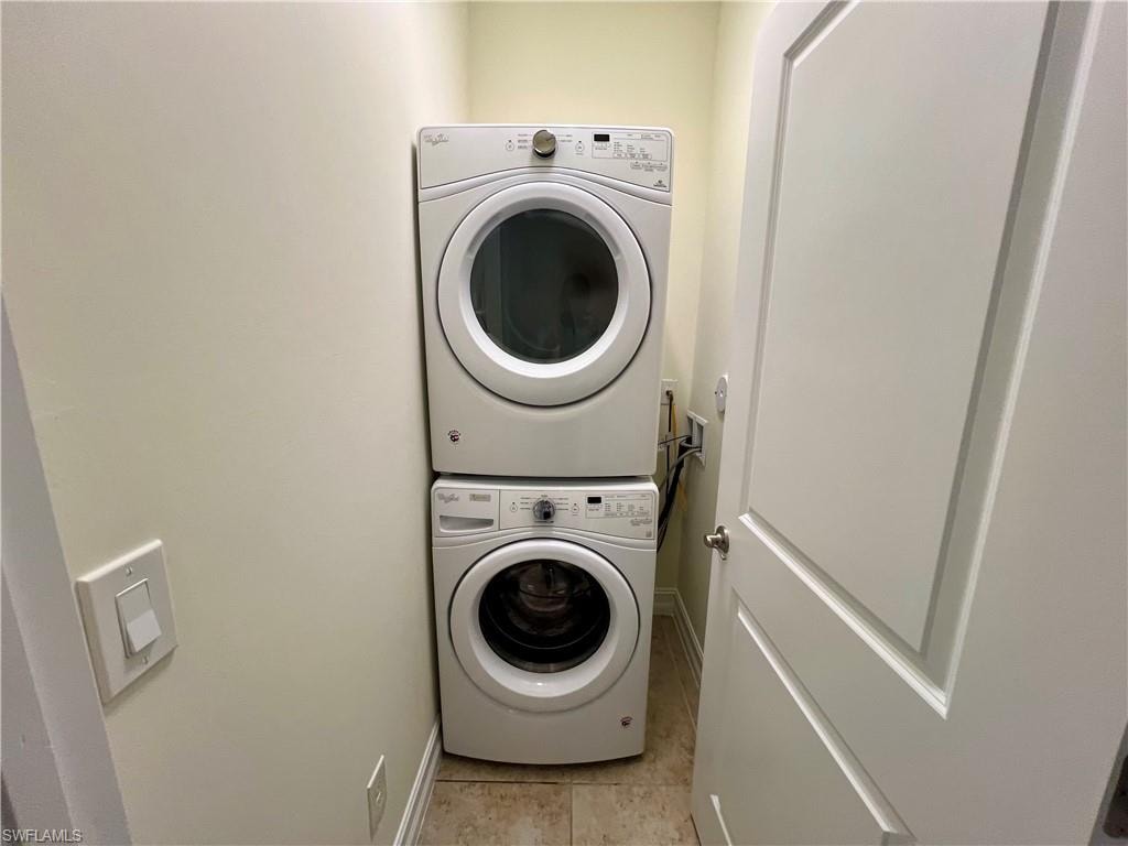 Washroom featuring stacked washer and clothes dryer and light tile patterned floors