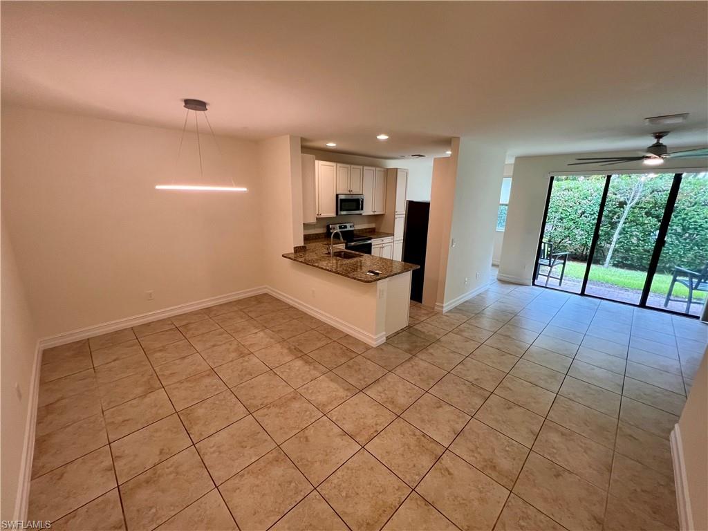 Kitchen with light tile patterned flooring, white cabinets, kitchen peninsula, and stainless steel appliances