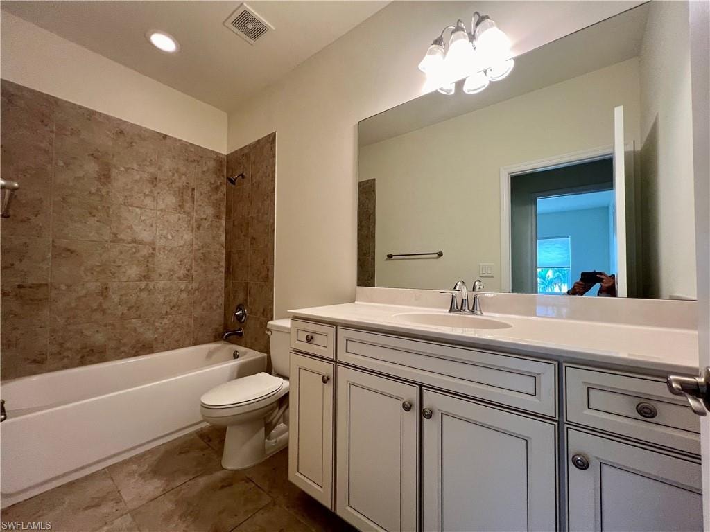 Full bathroom featuring vanity, tile patterned flooring, tiled shower / bath, and toilet
