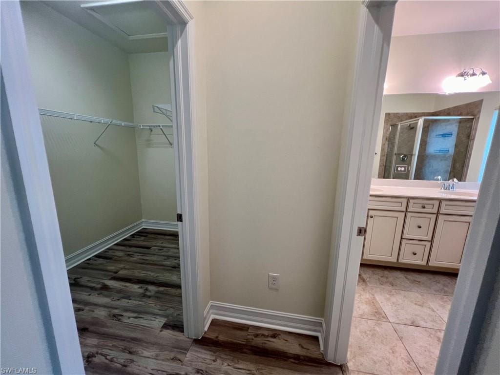 Bathroom with a shower with door, luxury vinyl plank / wood-style floors, and double vanity
