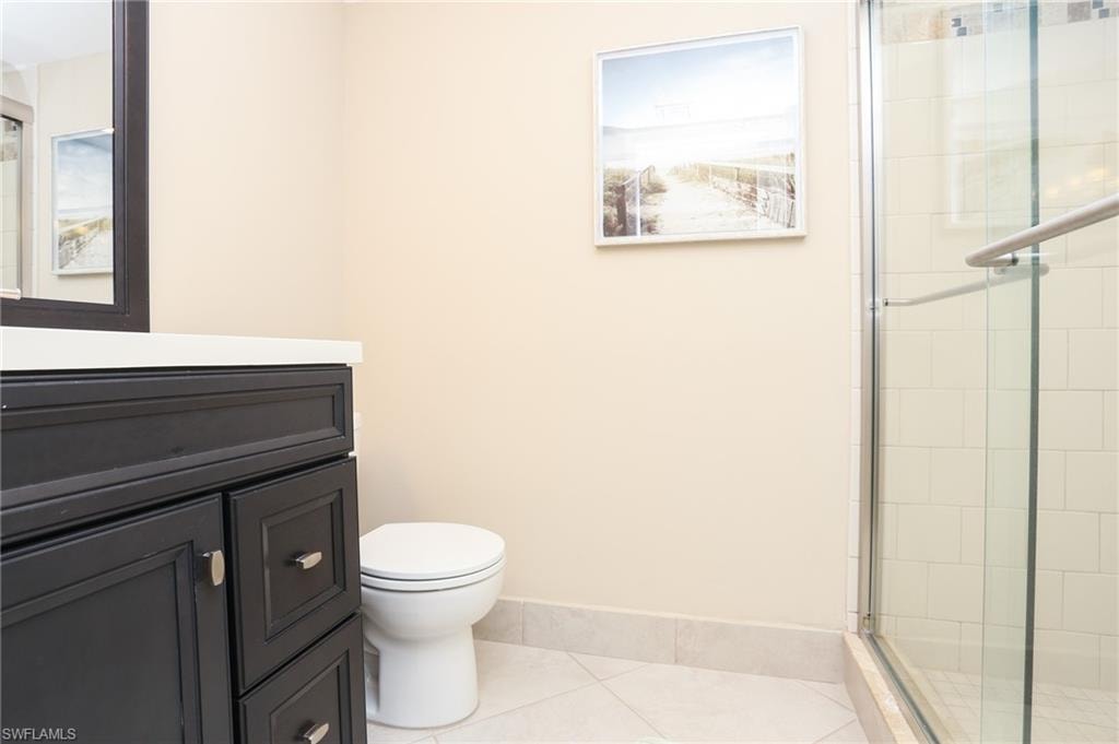 Full bathroom featuring a shower stall, tile patterned floors, vanity, baseboards, and toilet