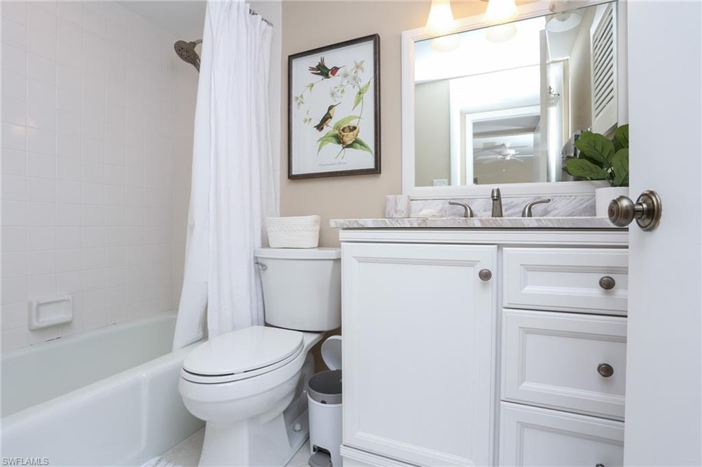 Bathroom with shower / tub combo, vanity, ceiling fan, and toilet