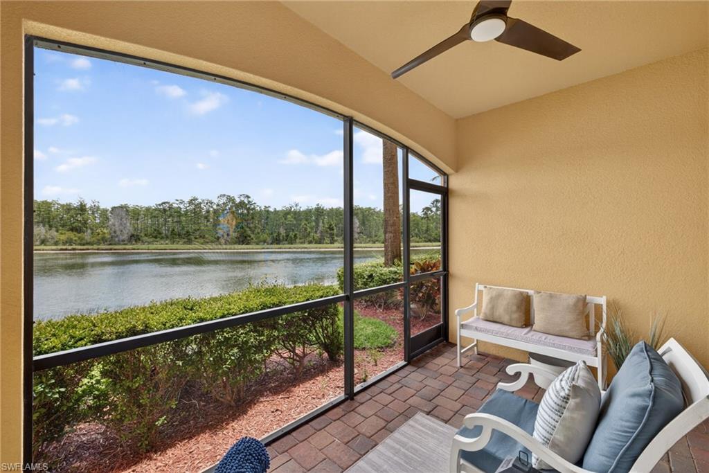 Screened lanai featuring a ceiling fan, brick paver flooring, and a water view