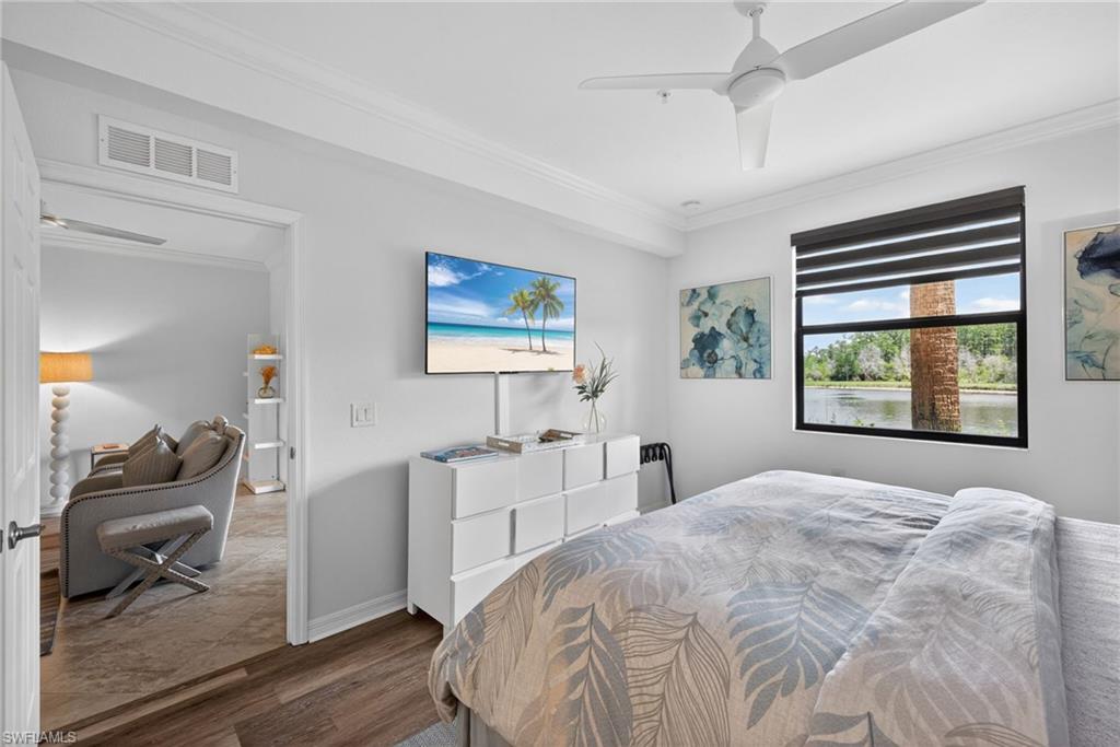 Bedroom featuring wood-finish flooring, a ceiling fan, crown molding, and a window with water and natural surroundings