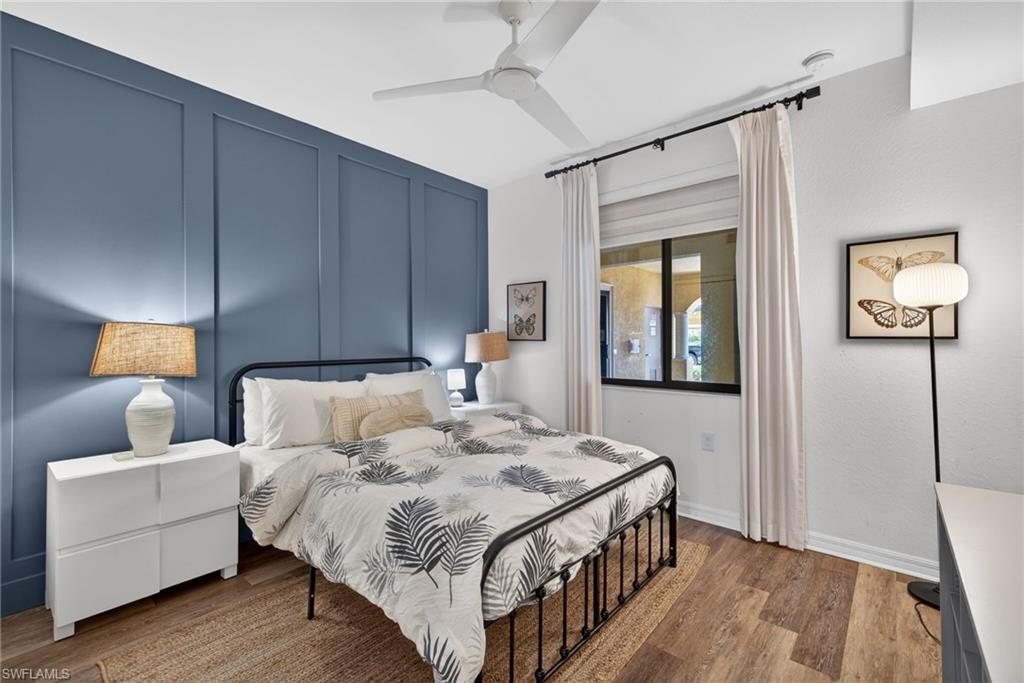 Bedroom featuring a paneled accent wall, wood-finish flooring, and a ceiling fan