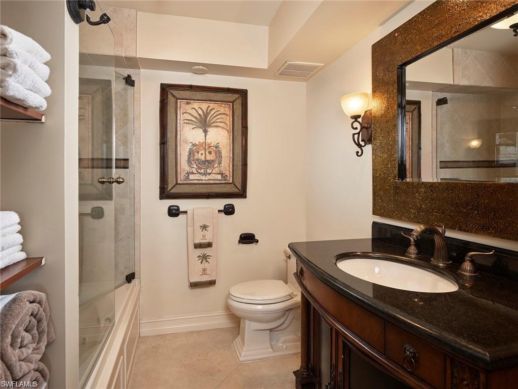 Full bathroom with tile patterned floors, toilet, enclosed tub / shower combo, and vanity