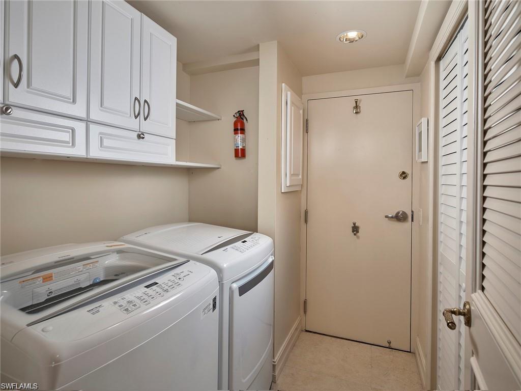 Laundry room with light tile patterned flooring, washer and clothes dryer, and cabinets