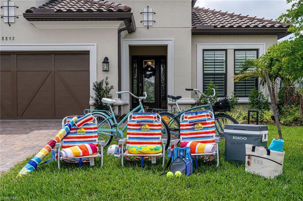 Stucco exterior featuring a tiled roof, paver driveway, and an attached garage with a panel door