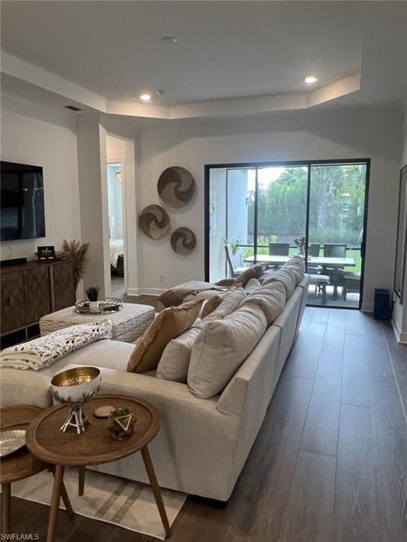 Spacious living area featuring wood-finish flooring, recessed lighting, and tray ceiling details