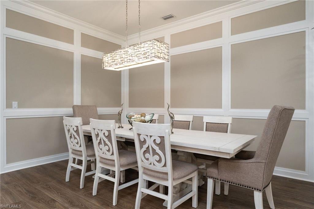 Dining area featuring wood-finish flooring, wainscoting with crown molding, and a rectangular chandelier