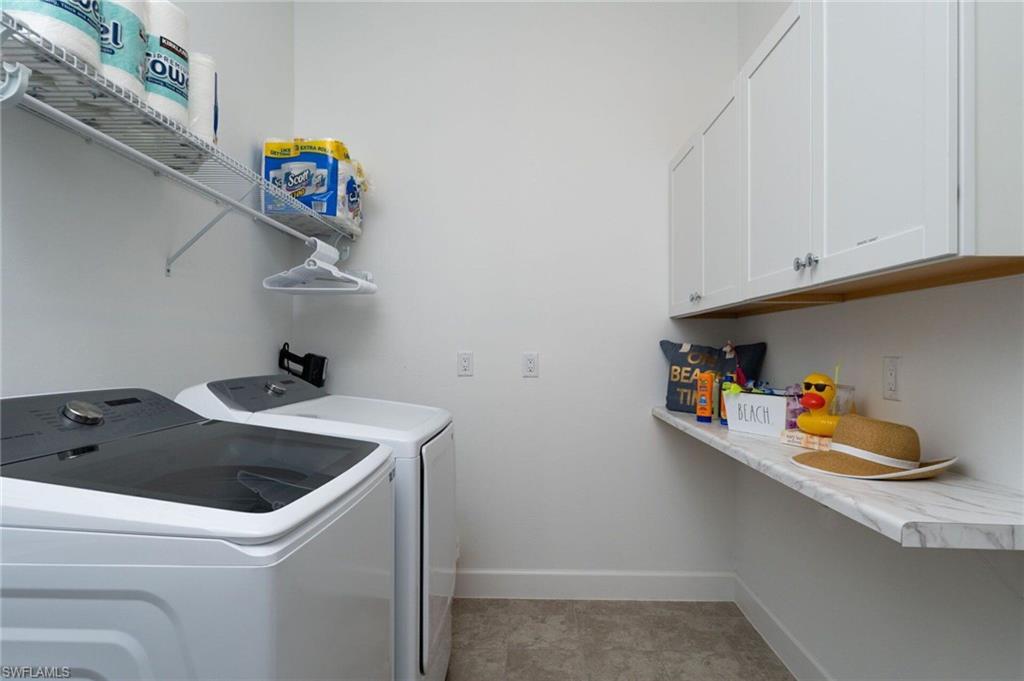 Dedicated laundry space featuring white shaker-style cabinetry, a white floating countertop, and a wall-mounted wire shelf