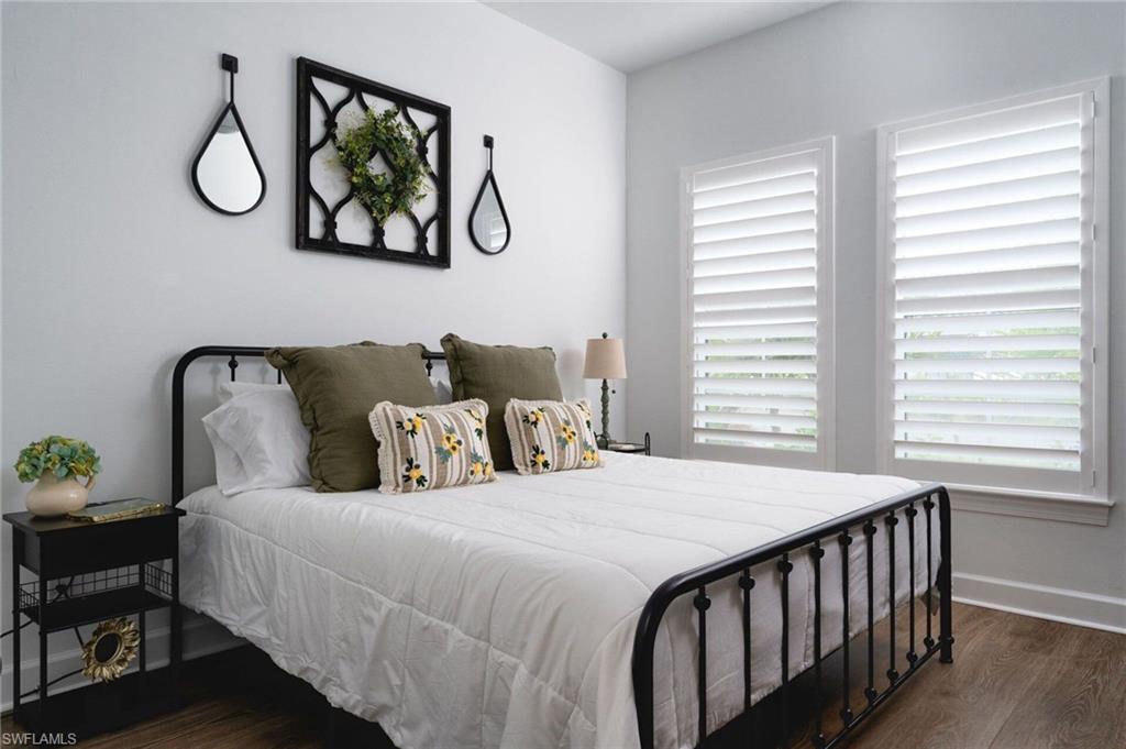 Bright room featuring two windows with white plantation shutters and wood-finish flooring