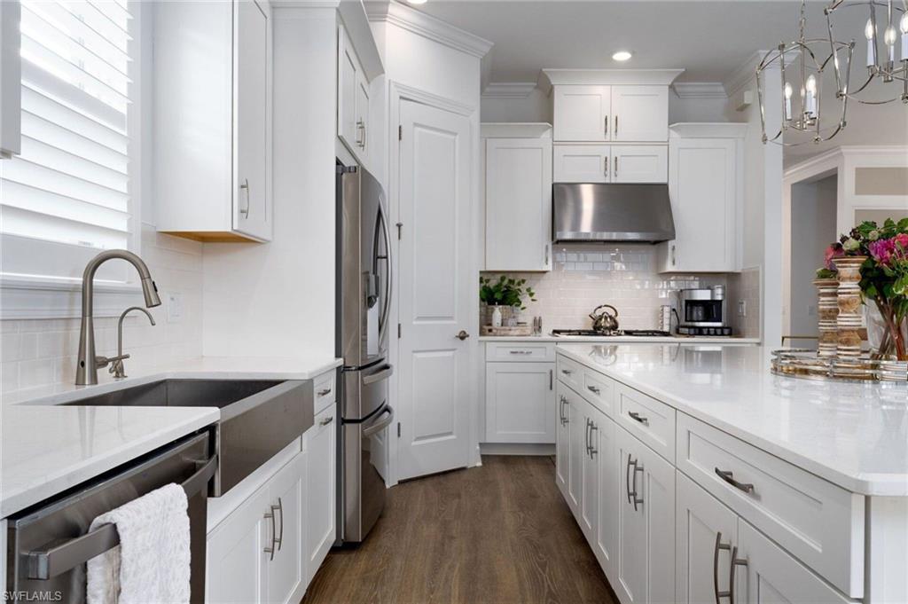 Contemporary kitchen featuring white cabinetry with brushed nickel hardware, white countertops, and wood-finish flooring