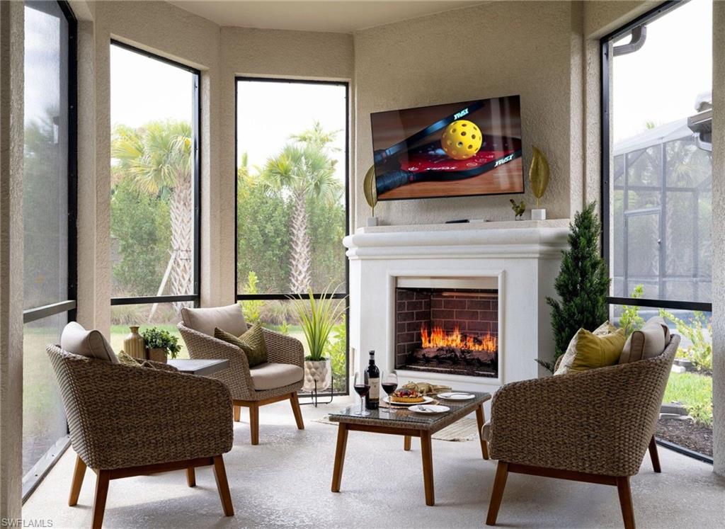 Screened outdoor living area featuring a built-in fireplace with a brick interior and a mantel, textured wall finishes, and multiple windows