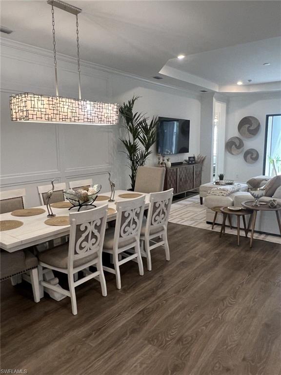 Open-concept interior featuring wood-finish flooring, a decorative linear chandelier, and recessed lighting