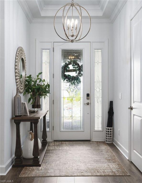 Entryway featuring a decorative transom, sidelight windows, wood-finish flooring, and crown molding