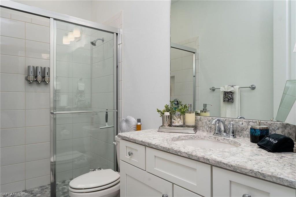 Bathroom featuring a shower with glass enclosure, white square wall tiles, and pebble floor