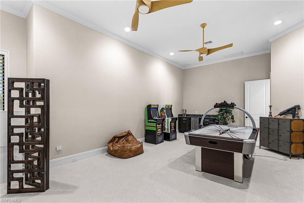 Carpeted recreation room featuring two ceiling fans, recessed lighting, and a window with blinds