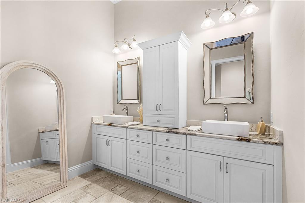 Double vanity with white cabinetry, vessel sinks, and stone countertops
