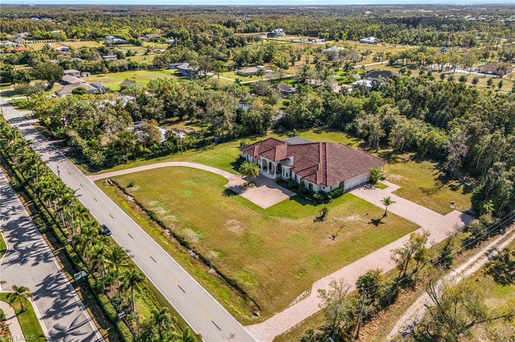 Expansive property featuring a Mediterranean-style residence with a terracotta tile roof, a circular driveway, and a three-car garage