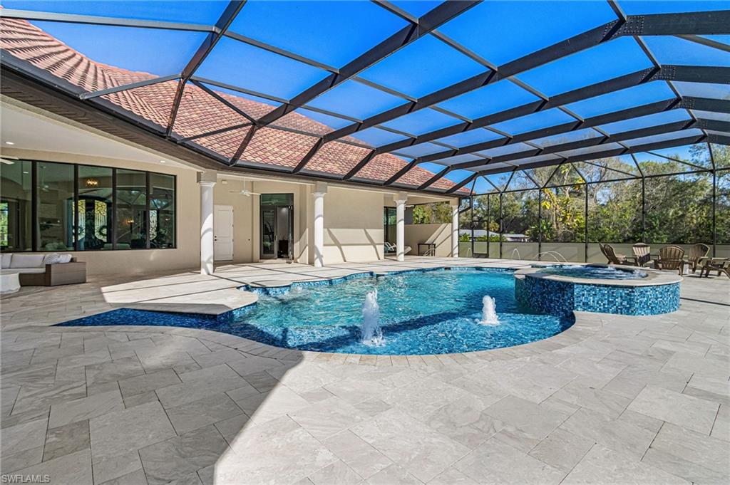 Expansive screened-in lanai featuring a large freeform pool with integrated spa, water features, and ample deck space