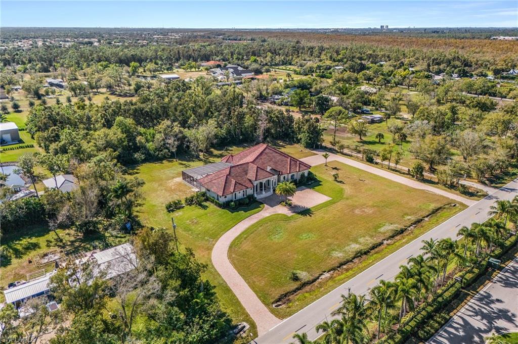 Expansive property featuring a Mediterranean-style residence with a terracotta tile roof, a curved paver driveway, and mature landscaping