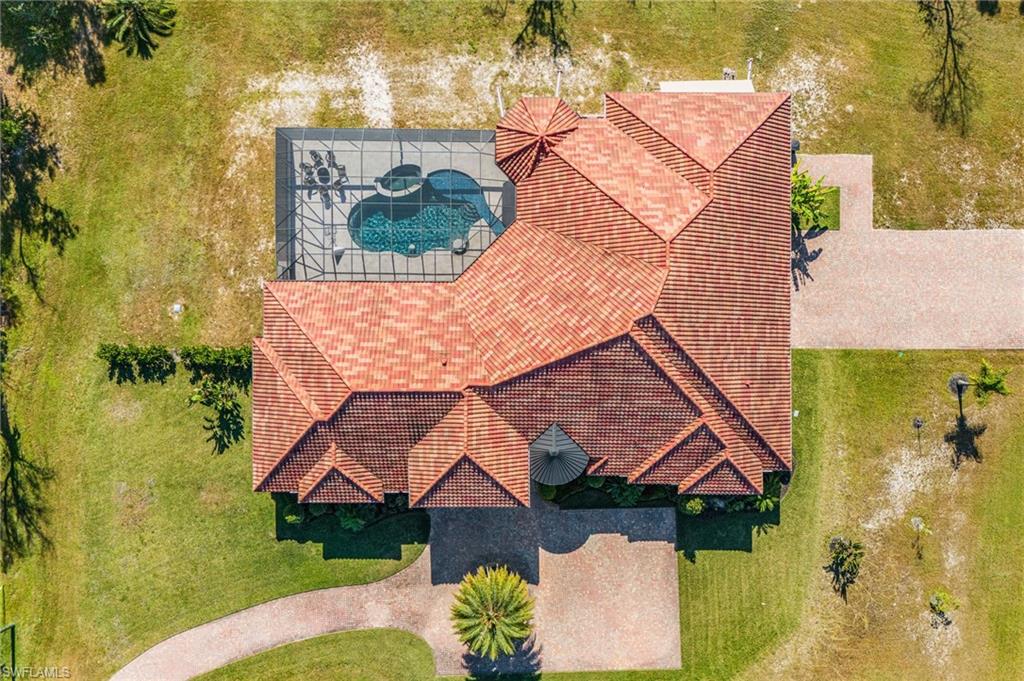 Expansive property featuring a red tile roof, covered swimming pool, and a circular driveway