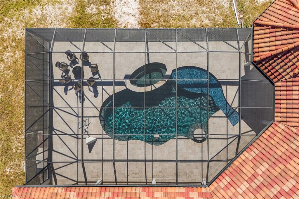 Screened-in pool area featuring a freeform pool, integrated spa, and concrete decking
