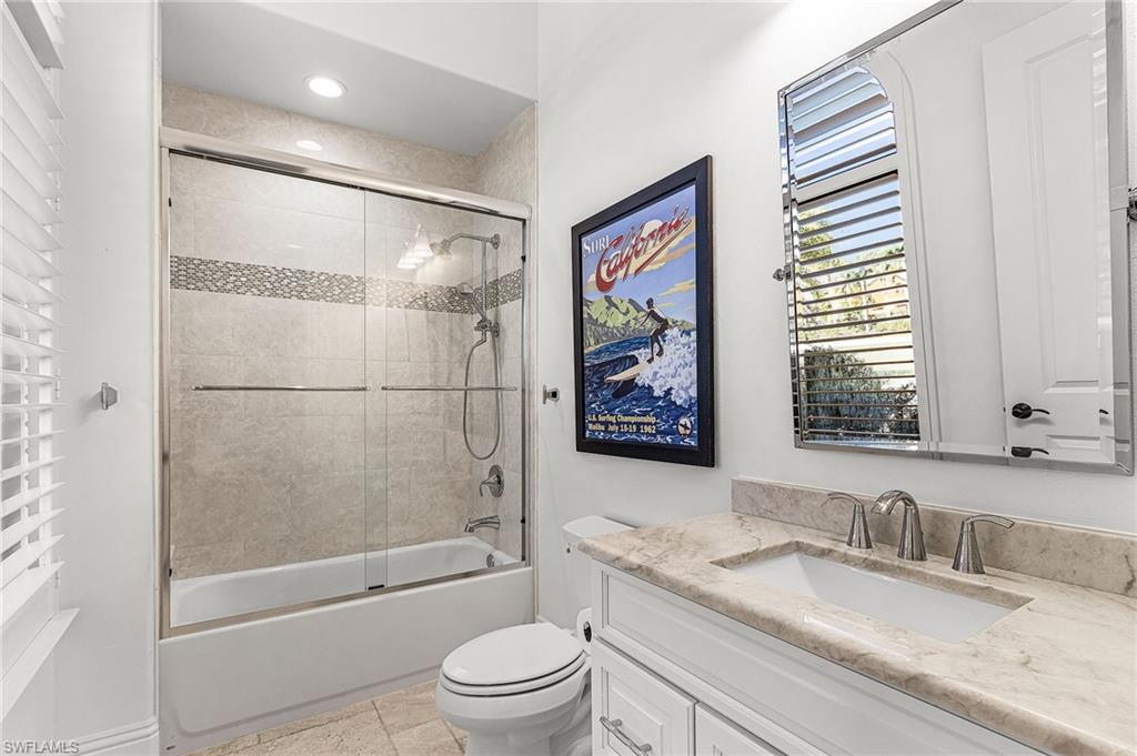 Bathroom featuring a spacious shower-over-tub with sliding glass doors, a decorative tiled accent band, and a chrome shower fixture
