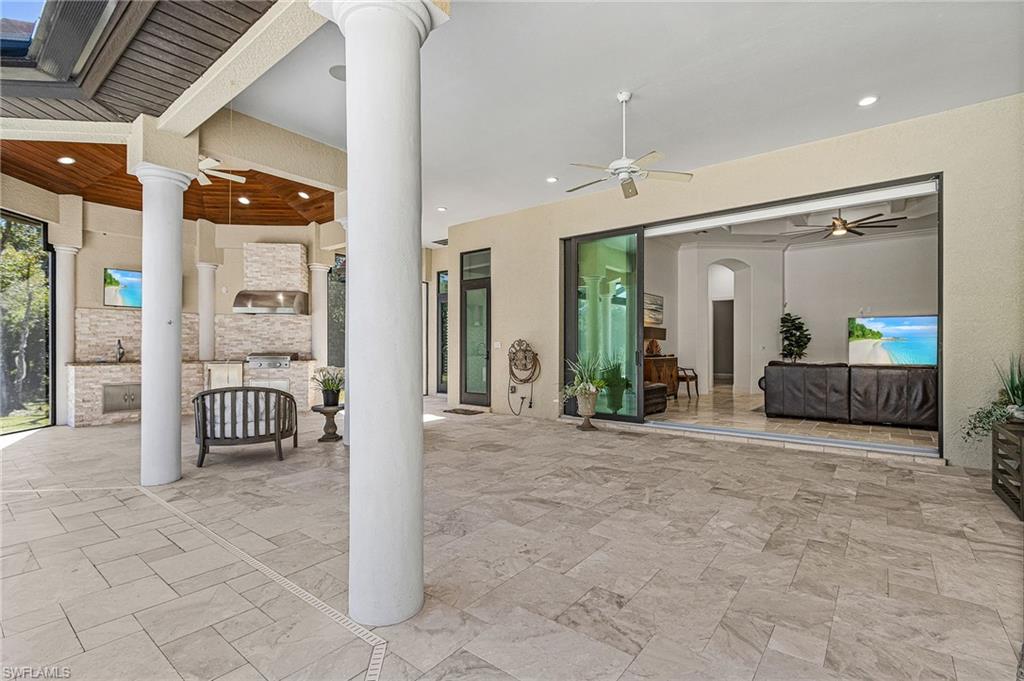 Expansive covered patio featuring large format rectangular tile flooring and an integrated outdoor kitchen with stacked stone accents