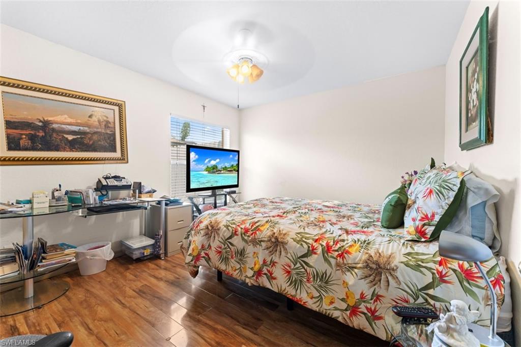 Bedroom featuring wood-finish flooring, a ceiling fan with integrated lighting, and a window with horizontal blinds