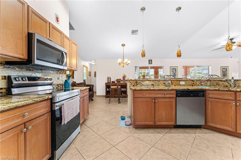 Kitchen featuring natural wood-finish cabinetry, stainless steel appliances, granite countertops, tile backsplash, and tile flooring