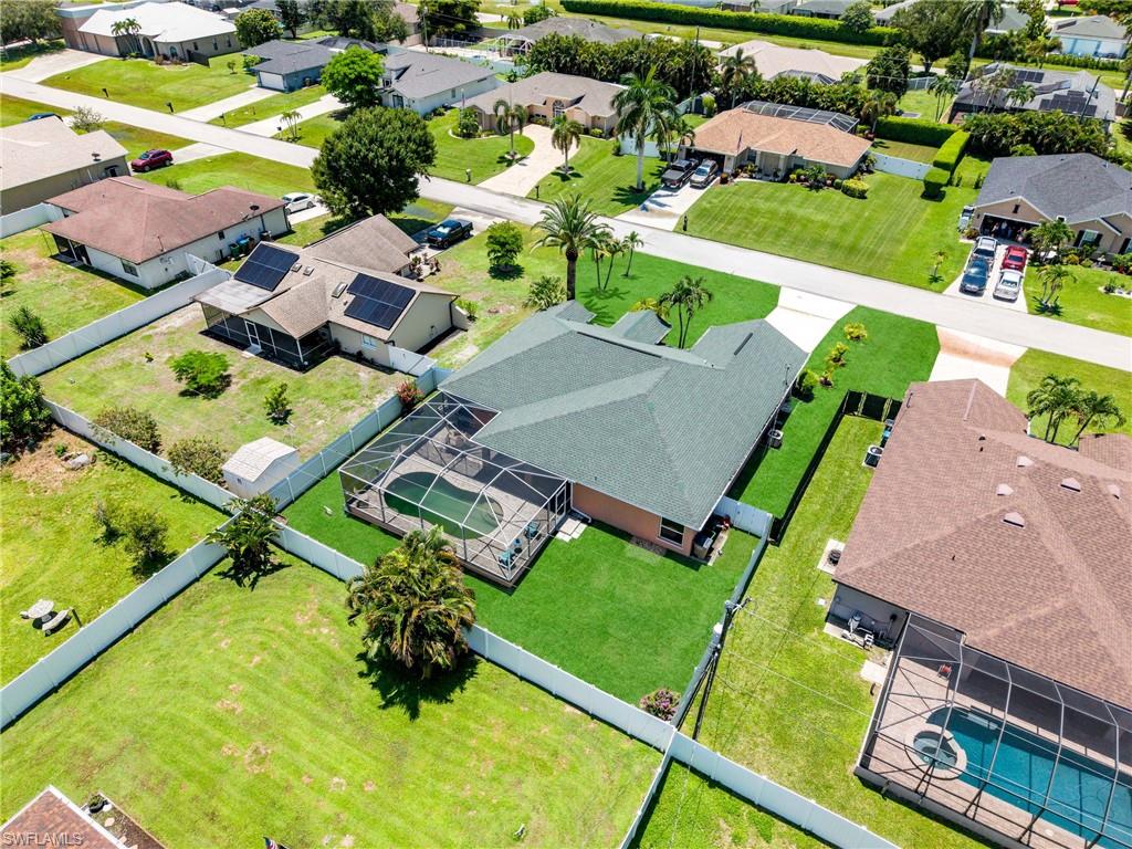Residential property featuring a screened-in pool, manicured lawn, and mature palm trees